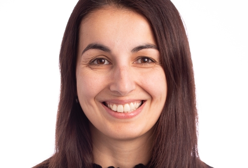 Close up of smiling middle aged woman wearing black turtleneck, posed against a white background