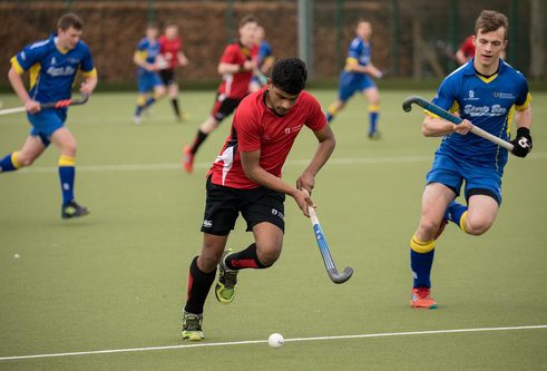 Person wearing red + black hockey kit holding a hockey stick, while competing in hockey match