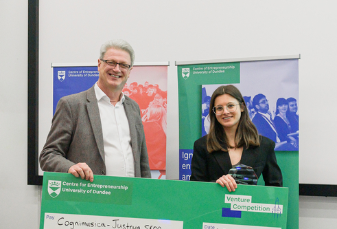 man and woman in suits holding a large green cheque