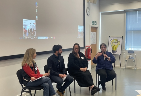 An image of a panel discussion at the meeting. The panel is of 3 women and one man sat on chairs at the front of a lecture theatre