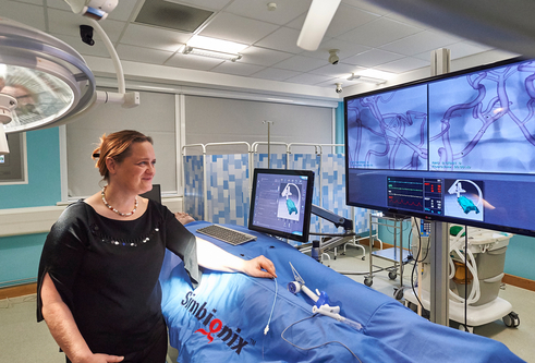 Iris Grunwald standing in an operating theatre looking at a large TV screen