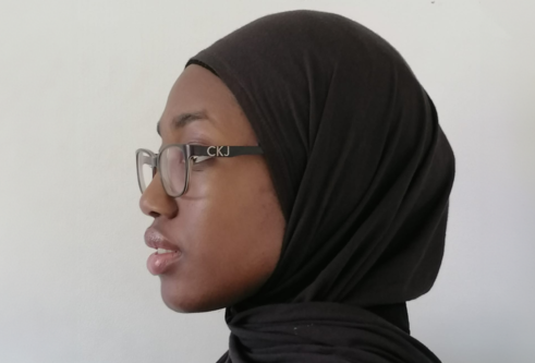 Side profile shot of Hanifah Sogbanmu, who wears a black hijab and glasses