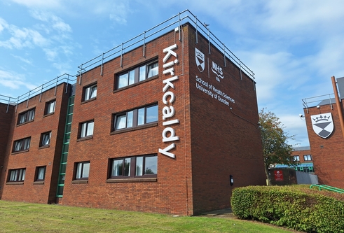 New signage at Kirkcaldy campus. The sign spells outs "Kirkcaldy" in vertical letters going down the side of a red-brick accomodation block