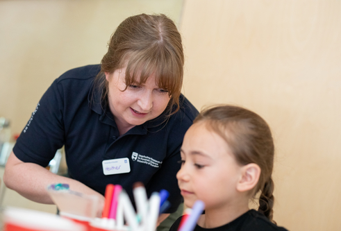 A member of the LRCFS public engagement team aids a child in performing a chromatography experiment