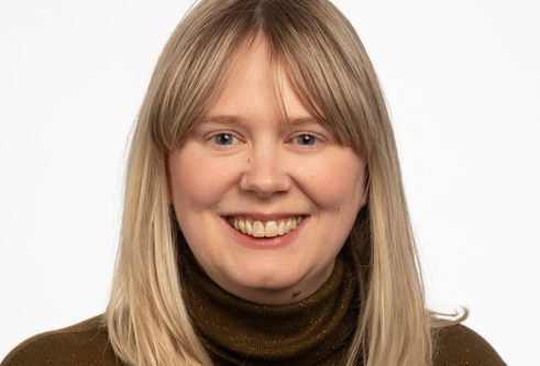 Head and shoulders shot of woman with medium length blond hair looking at the camera and smiling 