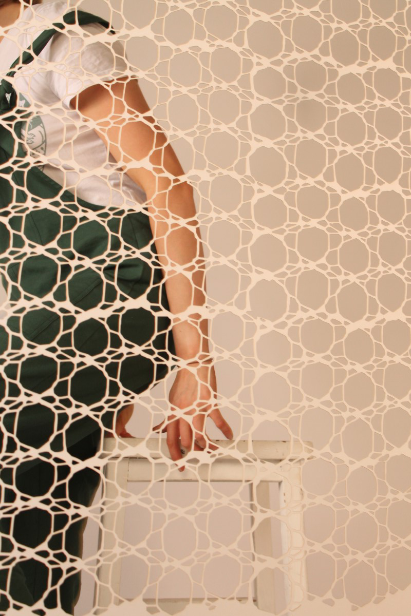 paper, laser cut curtain with a girl taking a seat behind it in a studio setting