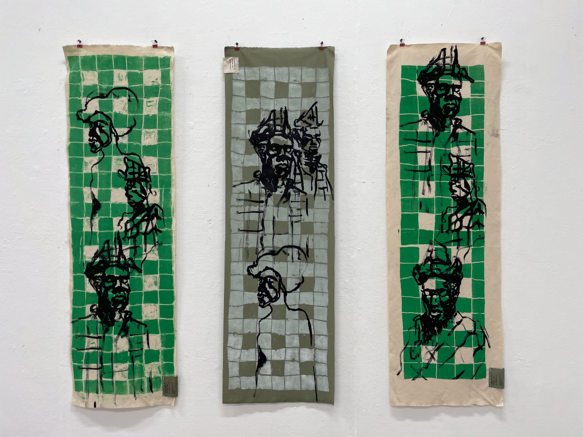 Three tapestries showing faces drawn with black ink on green squares.